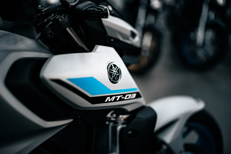 Lateral do tanque da MT-03, branca com faixa azul e o emblema Yamaha.